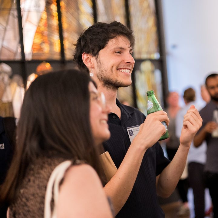 Aaron laughing with a drink at a university science conference reception